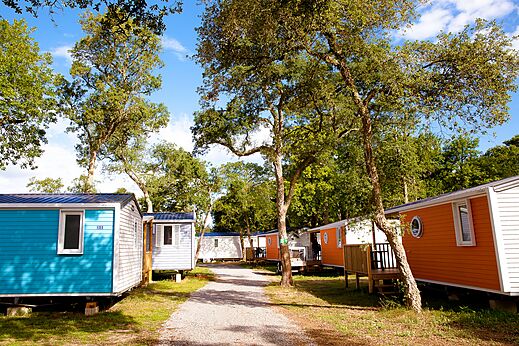 Colorful mobile homes under trees at VAGUES OCEANES Boudigau campsite in LABENNE OCEAN (40).