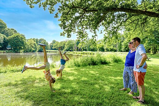 Children doing handstands by lake, adults watching at camping CAPFUN Breteche (85).