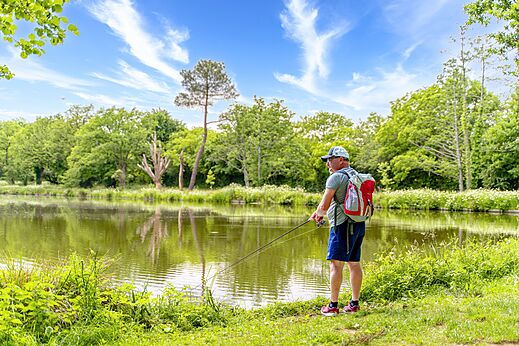 Man fishing by a green pond at CAPFUN Breteche campsite in Les Epesses (85).