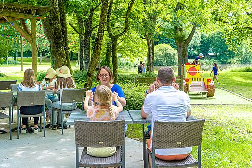 Family dining on outdoor terrace, playground, CAPFUN Breteche camping Les Epesses (85).