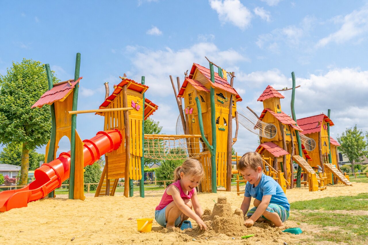 Children playing in sandpit, wooden playground at CLICOCHIC Brise de Cabourg campsite.