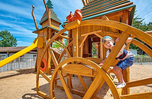 Wooden playground with slide and child at camping CLICOCHIC Cabanes d Oléron in ST GEORGES D'OLERON (17).