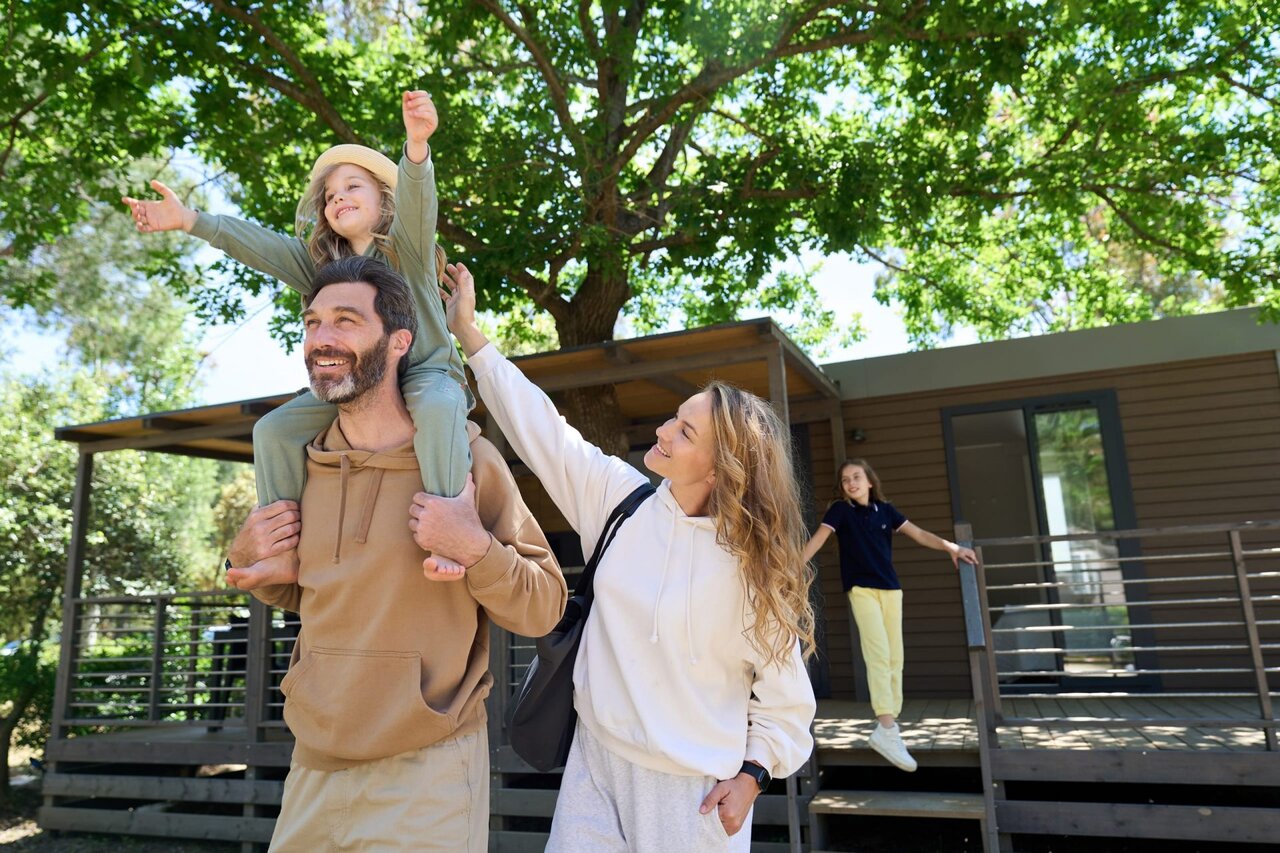 Happy family in front of mobile home at CAPFUN Campo dei Fiori campsite, Rosignano Marittimo.