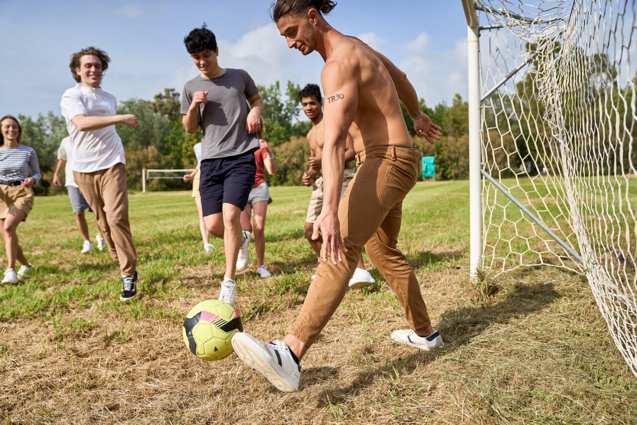 Playing football on sports field at CAPFUN Campo dei Fiori campsite.