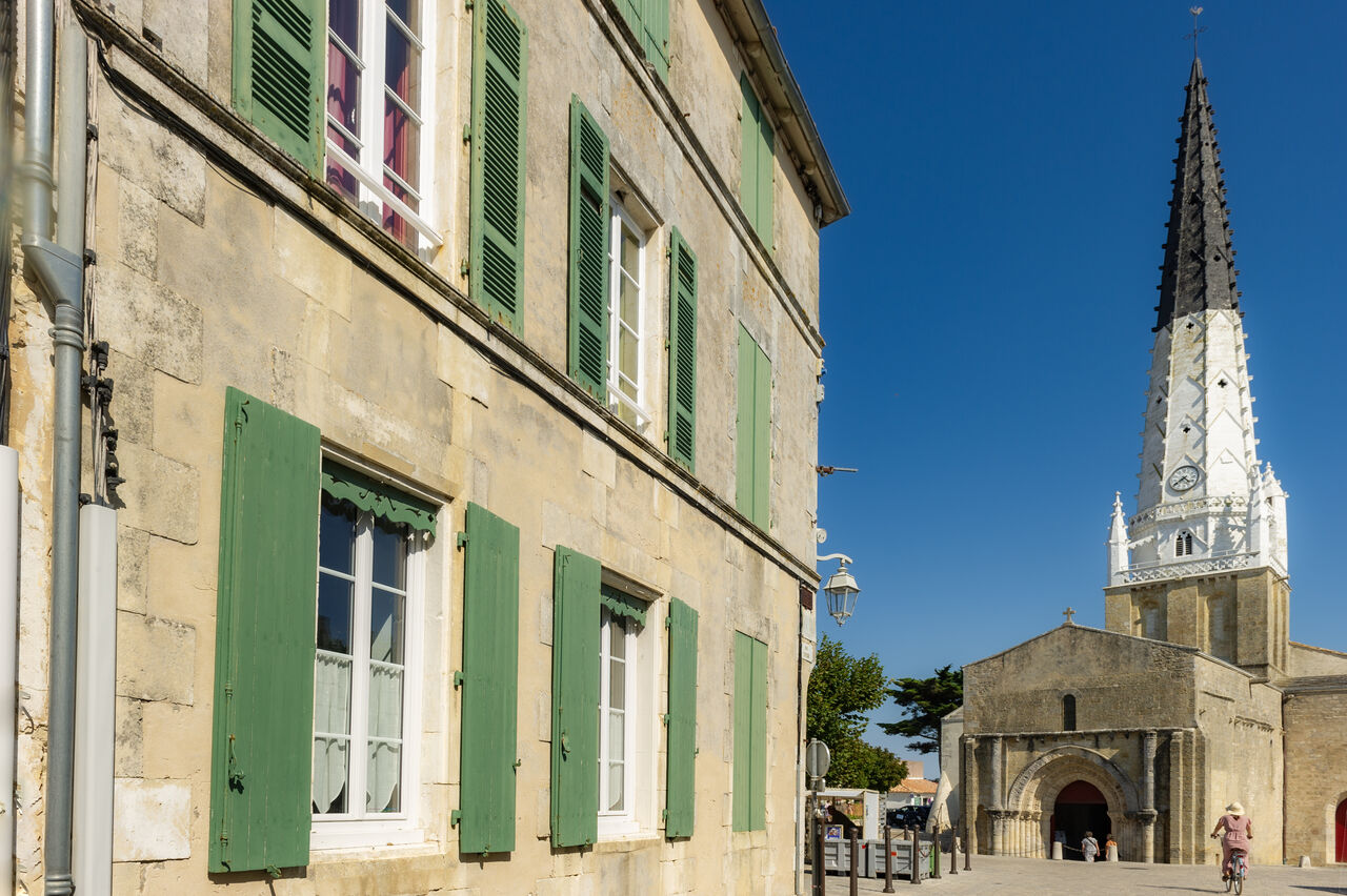Pointed church steeple and old houses with green shutters, in Ars-en-R�.