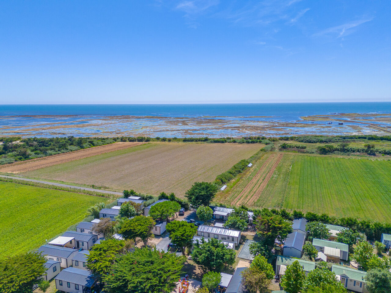 Mobile homes, fields and sea, aerial view at CLICOCHIC Camp du Soleil campsite.