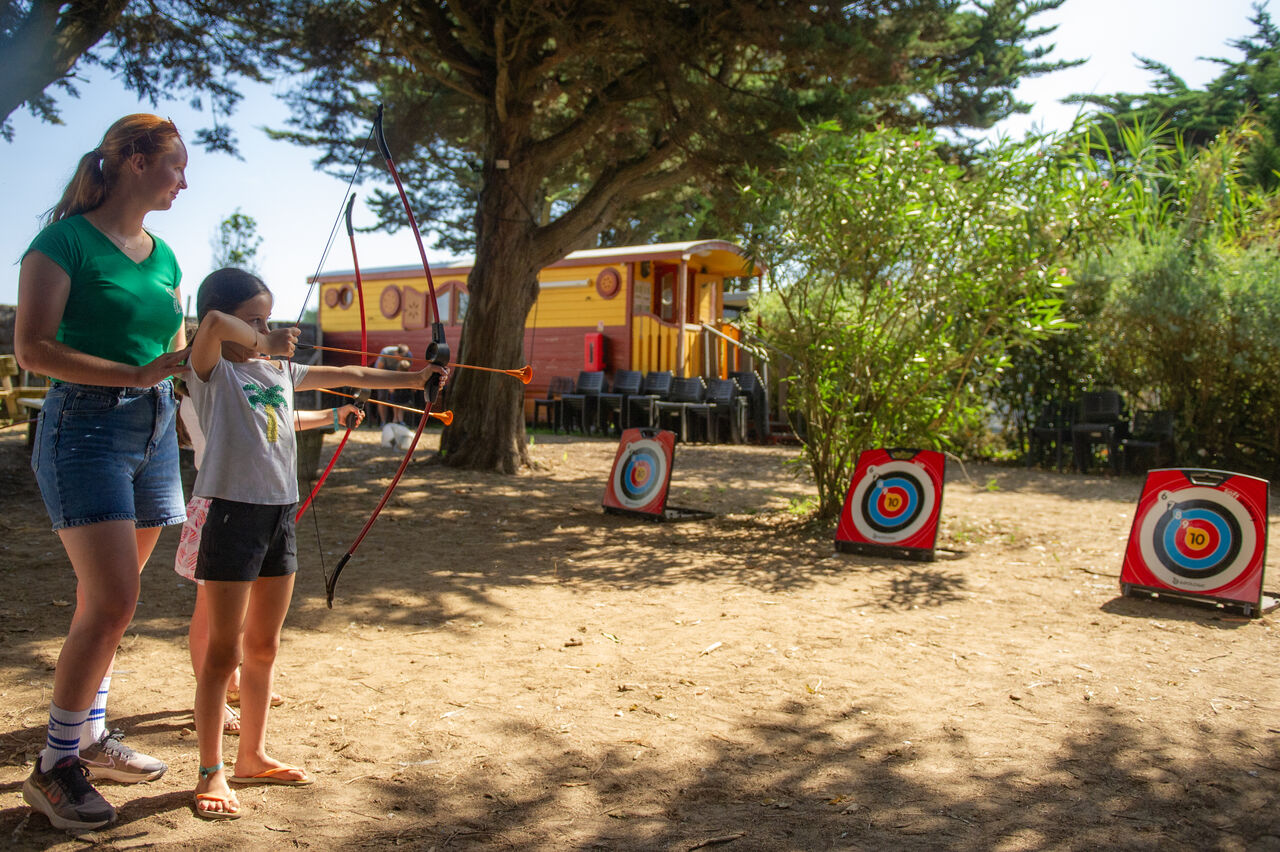Child practicing archery with instructor at CAPFUN Cenic campsite in Ars-en-R�.