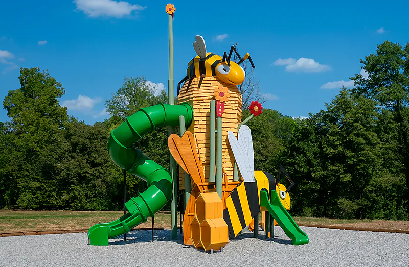 Bee-themed playground with green slides at CLICOCHIC Castillon de Provence campsite.