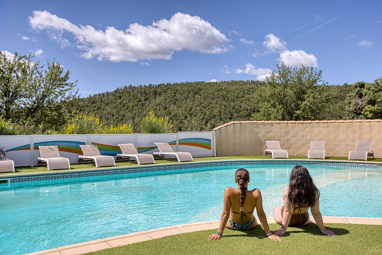 Outdoor pool, sun loungers, two women at CLICOCHIC Castillon de Provence campsite.