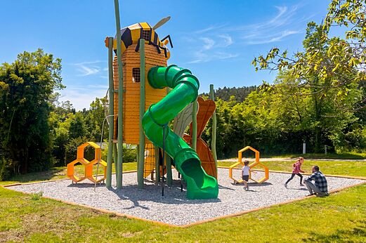 Bee-themed playground with green slide at camping CLICOCHIC Castillon de Provence (04).