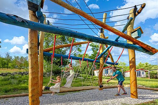 Wooden play structure and rope swing at camping CLICOCHIC Castillon de Provence.