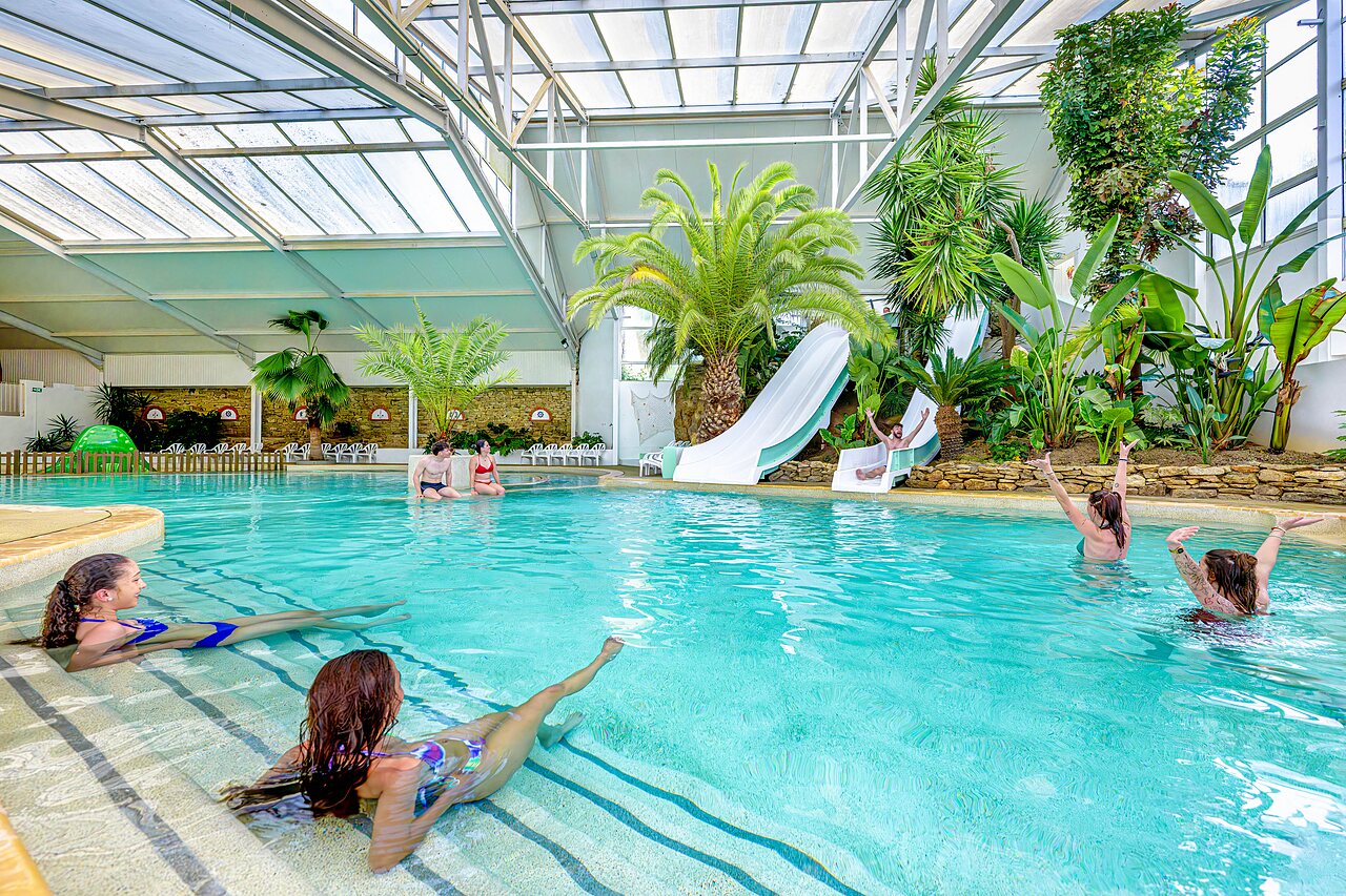 Covered swimming pool with slides and palm trees at CAPFUN Cenic campsite in PENESTIN (56).