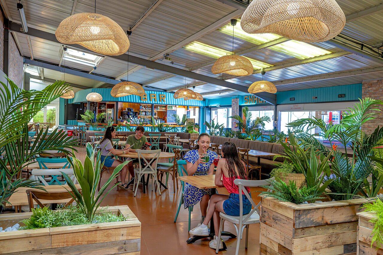 Indoor bar and restaurant area with guests at CAPFUN Cenic campsite in PENESTIN (56).