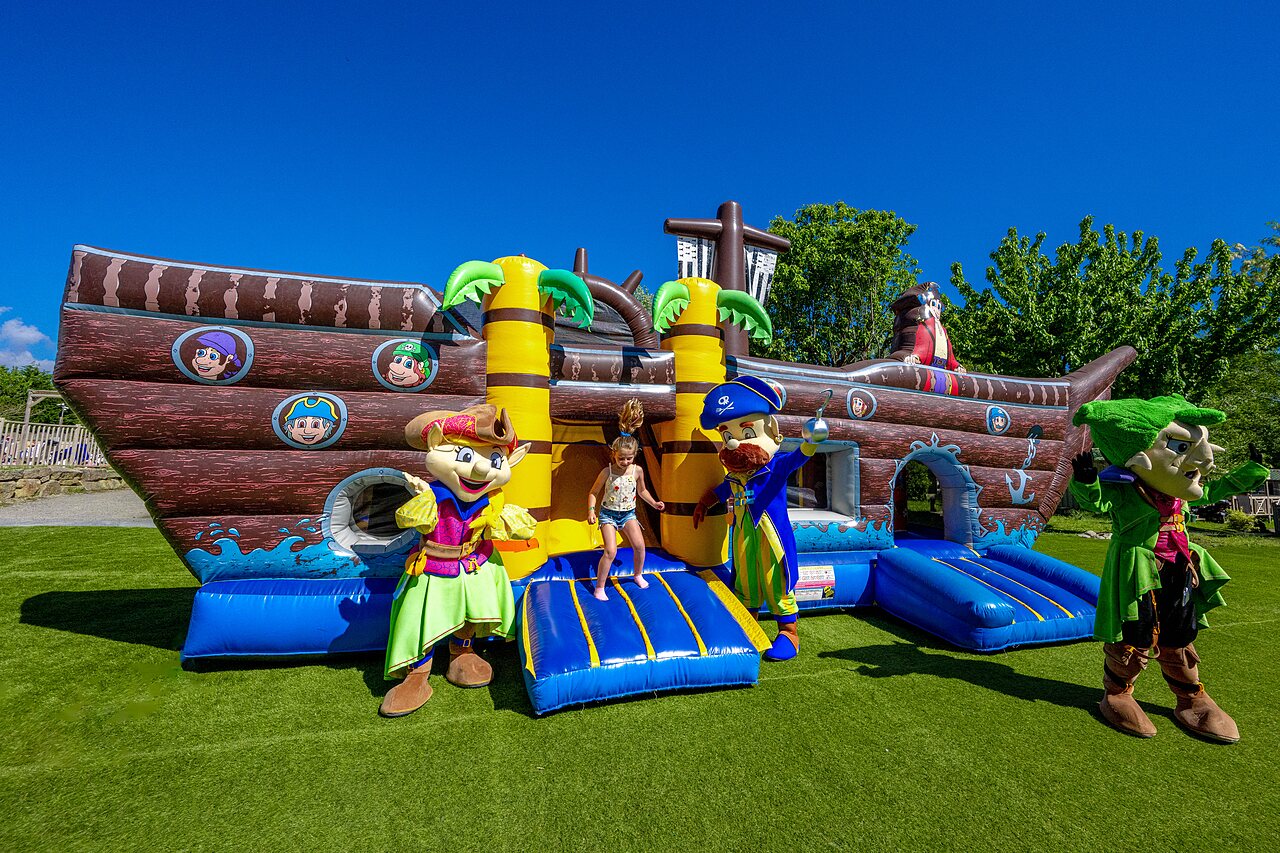 Inflatable pirate ship bouncy castle with mascots and child at CAPFUN Cenic campsite in PENESTIN (56).