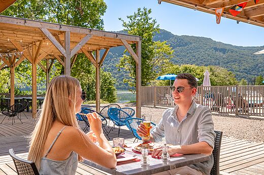 Couple dines on restaurant terrace with lake view at CLICOCHIC Chancia campsite (01).