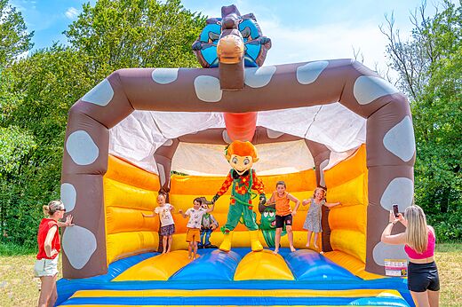 Giant inflatable bouncy castle with children and mascot at CLICOCHIC Chancia campsite in Chancia (01).