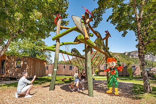 Wooden play structure with swings and mascot at camping CLICOCHIC Chancia in Chancia (01).