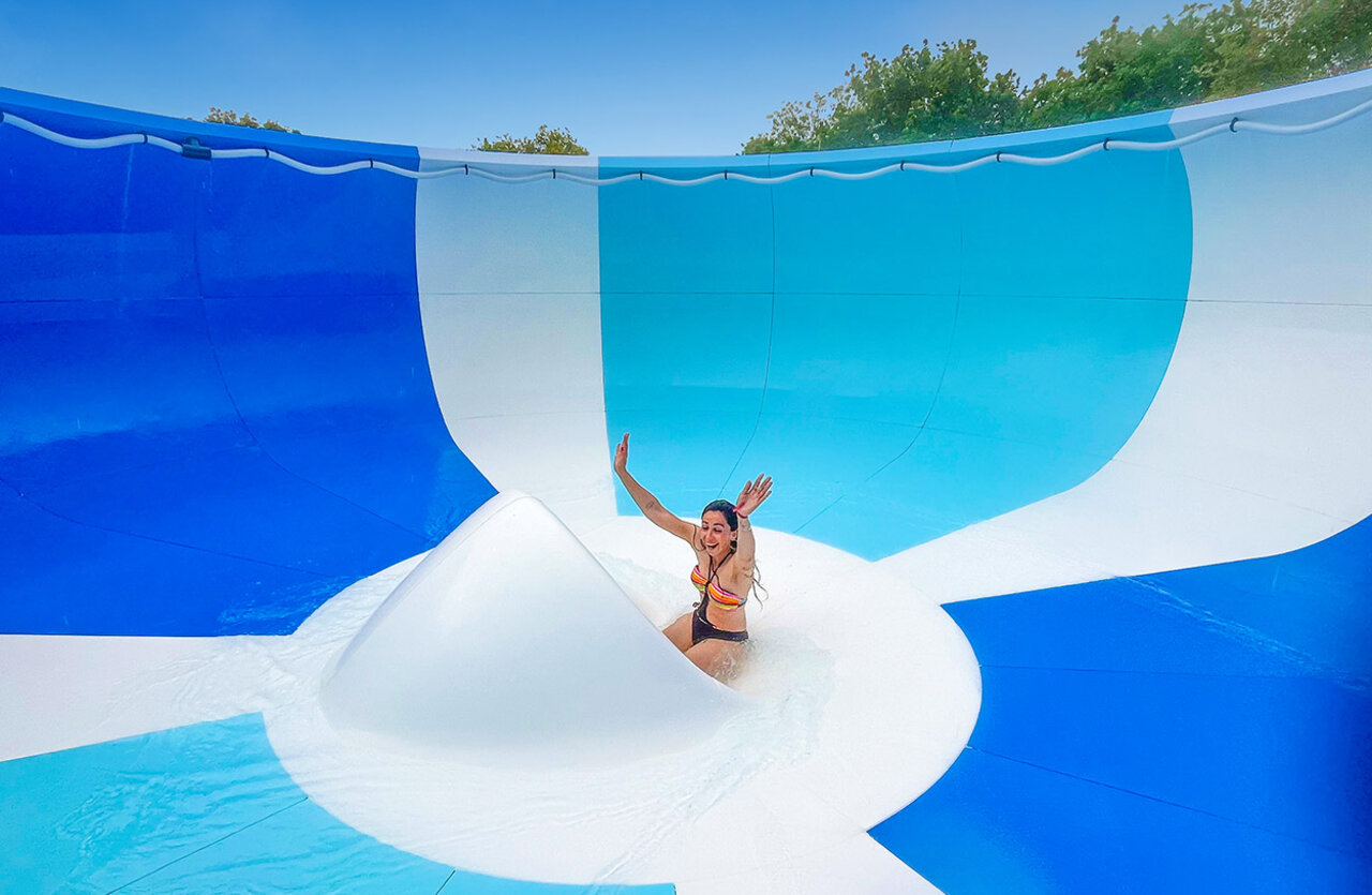 Giant water slide with smiling woman at VAGUES OCEANES Domaine les Charmilles campsite.