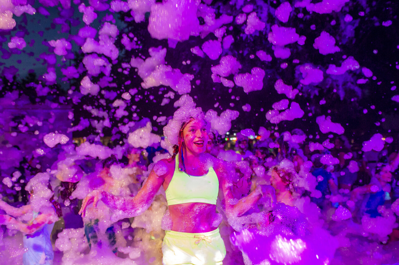 Smiling young woman foam party at VAGUES OCEANES Domaine les Charmilles campsite.