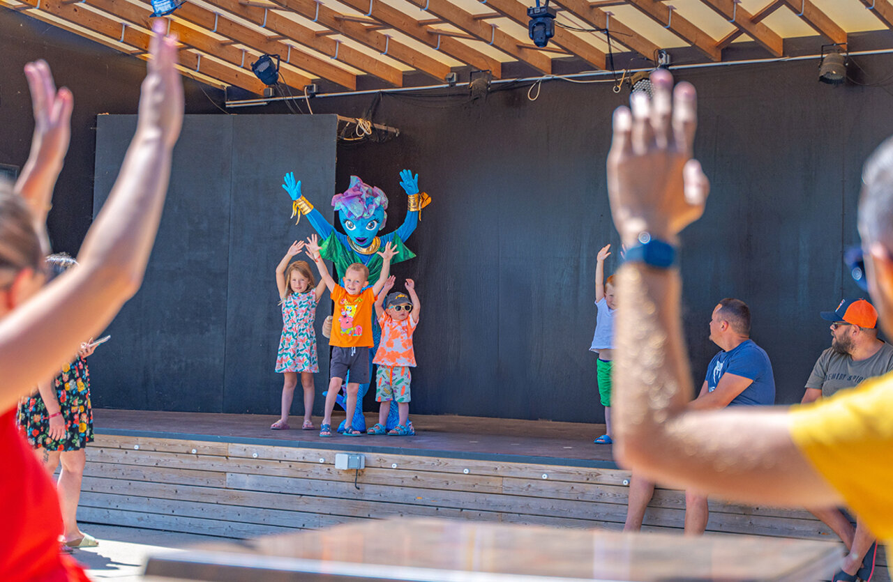 Children's entertainment with mascot on stage at VAGUES OCEANES Domaine les Charmilles campsite.