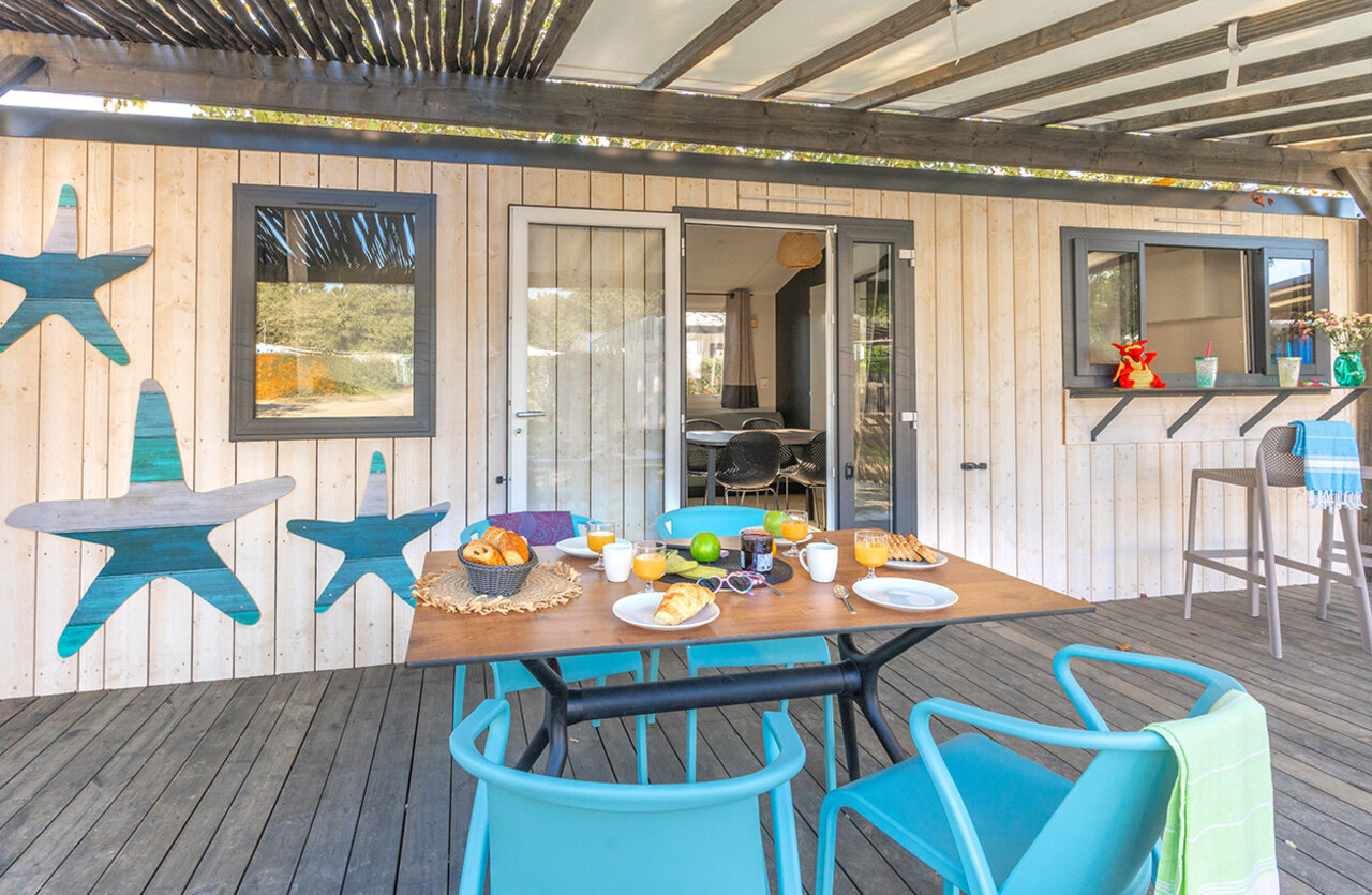 Breakfast on covered terrace of modern mobile home at VAGUES OCEANES Domaine les Charmilles campsite in Saint-Laurent-de-la-Pr�e (17).