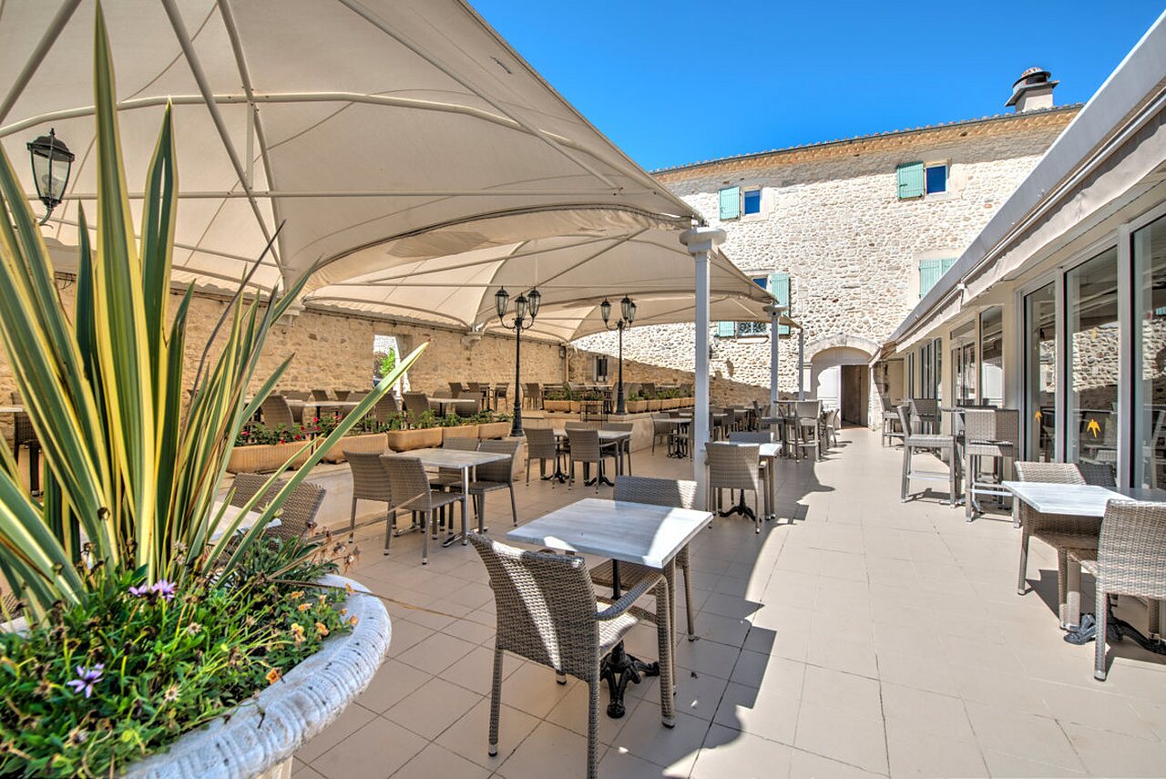 Shaded restaurant and bar terrace, tables, at camping CLICOCHIC Ch�teau de Boisson (30).