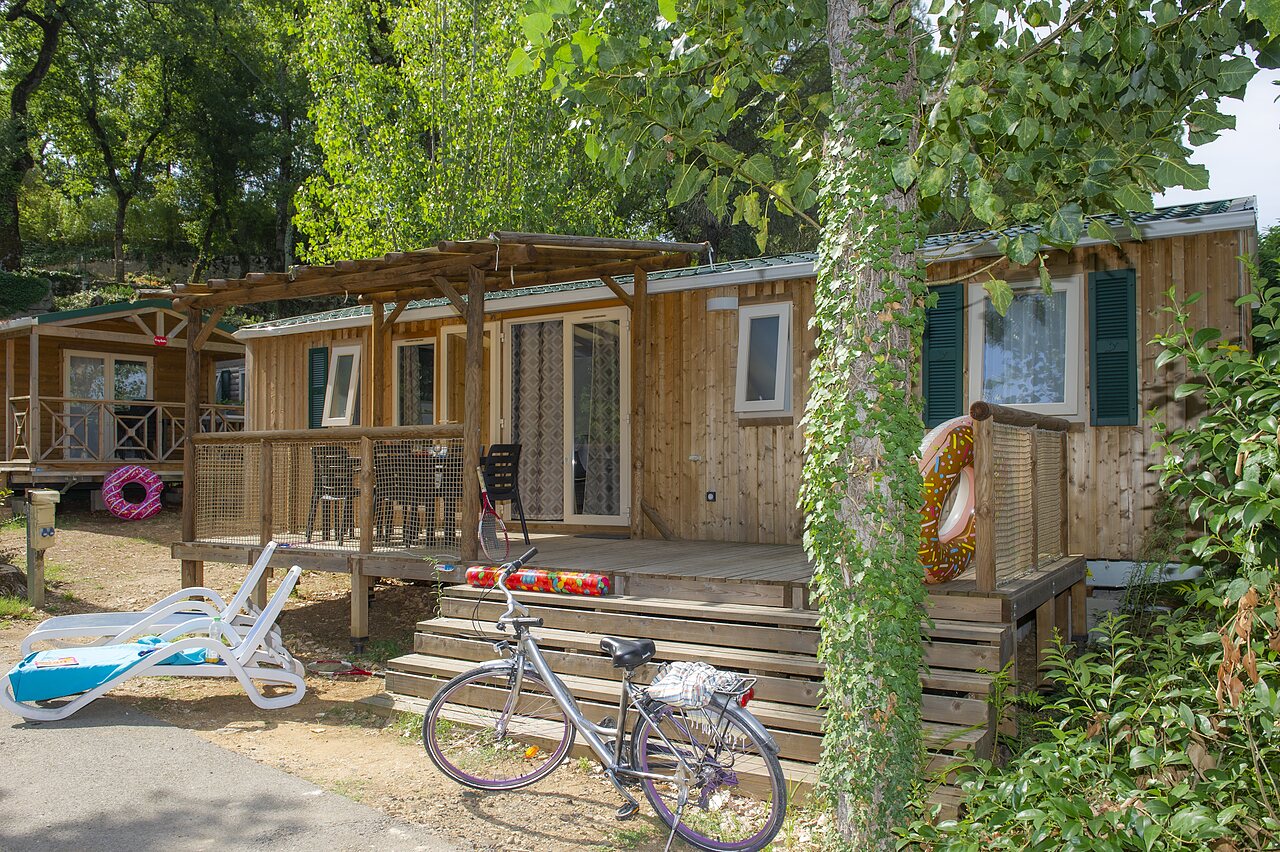 Wooden mobile home with terrace and bicycle at CLICOCHIC Ch�teau de Boisson campsite in All�gre-les-Fumades (30).