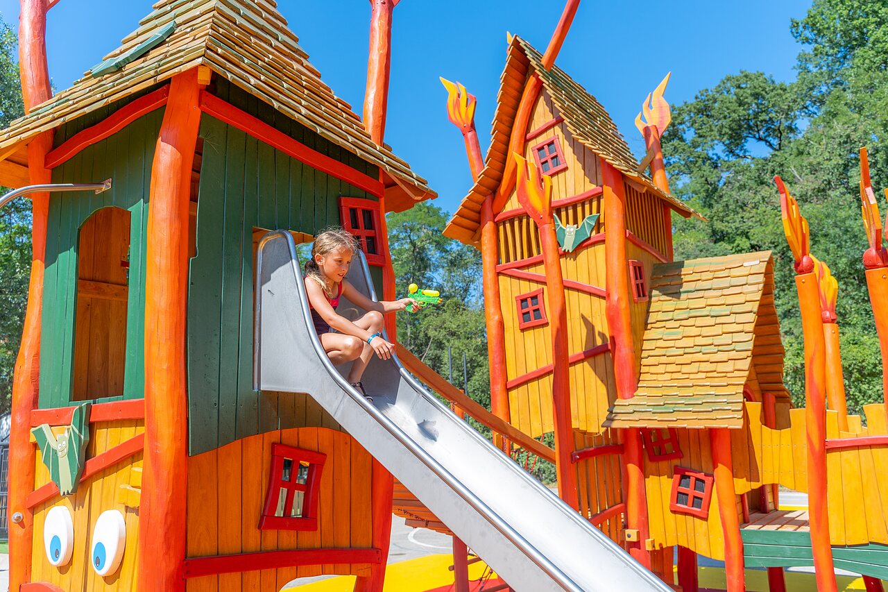 Colorful playground with slide and child at CLICOCHIC Ch�teau de Boisson campsite in All�gre-les-Fumades (30).