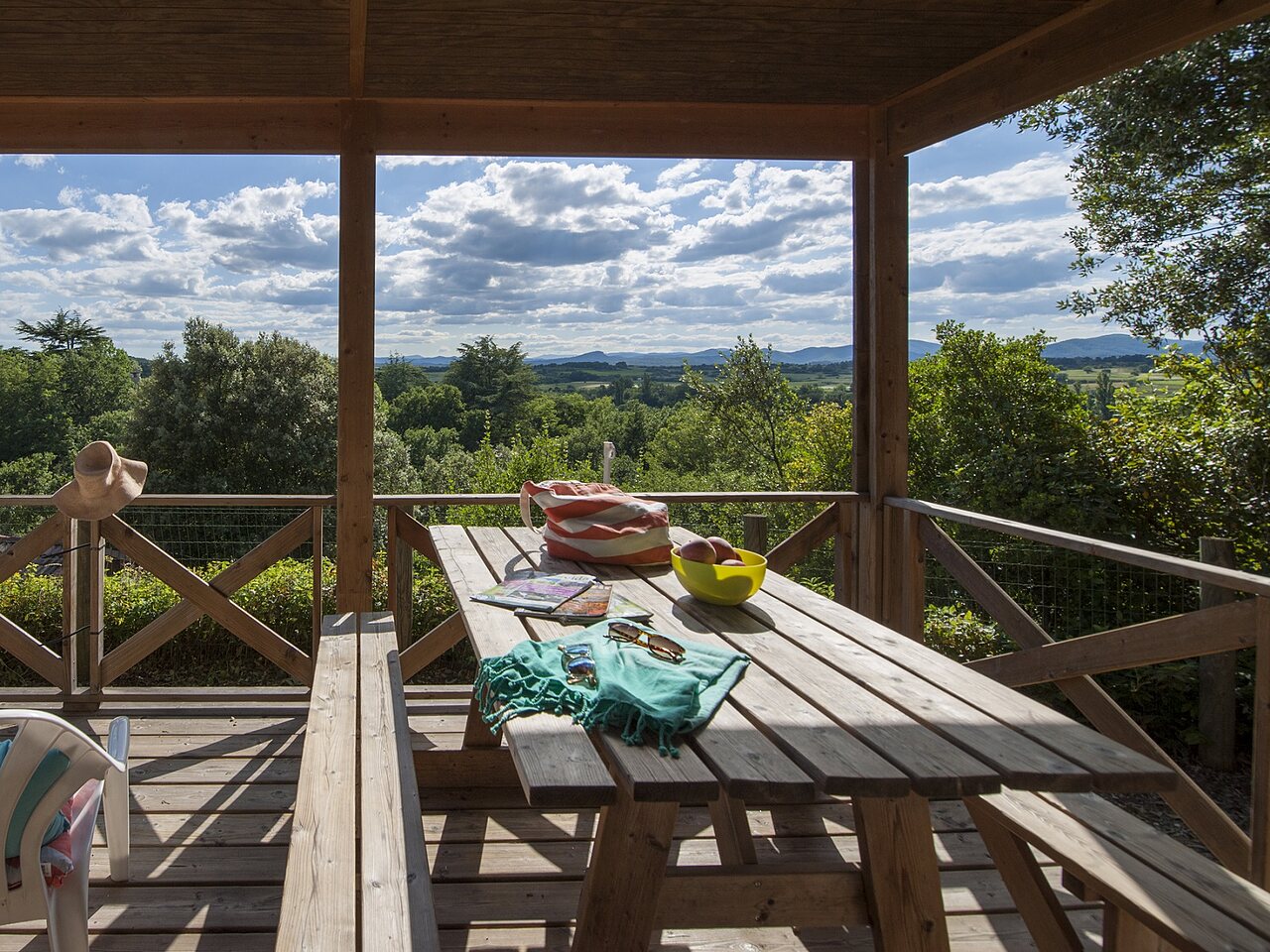 Wooden terrace, table, panoramic view at CLICOCHIC Ch�teau de Boisson campsite.