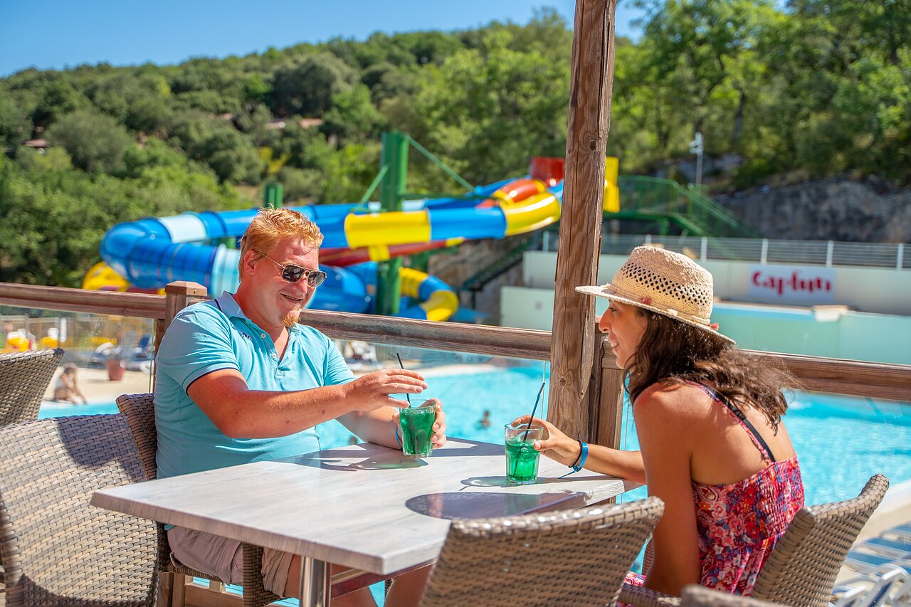 Pool bar, couple, water slides, CLICOCHIC Ch�teau de Boisson campsite All�gre-les-Fumades.