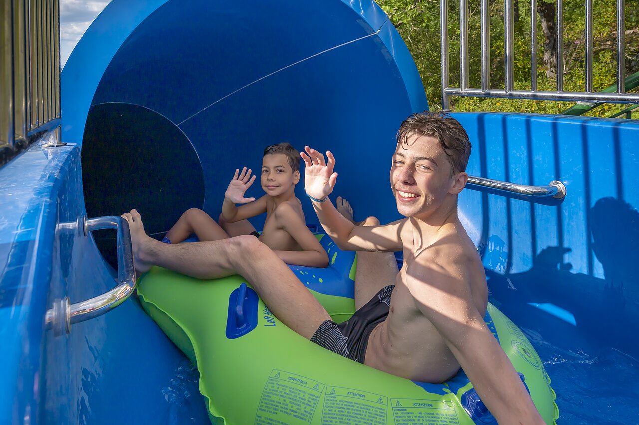 Water slide with smiling children on inflatable ring at CLICOCHIC Ch�teau de Boisson campsite in All�gre-les-Fumades (30).