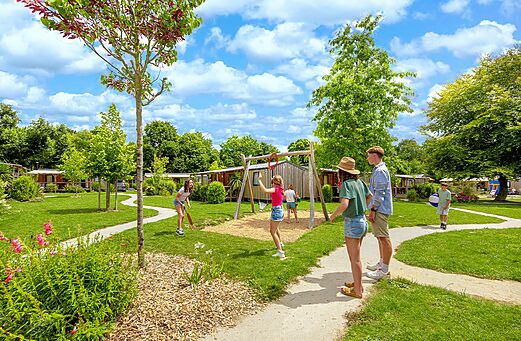 Playground with swing set and children at CAPFUN Château de Galinée campsite in SAINT CAST LE GUILDO (22).