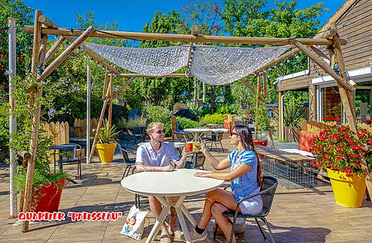 Shaded restaurant terrace with couple at CAPFUN La Chênaie campsite in PORNIC (44).
