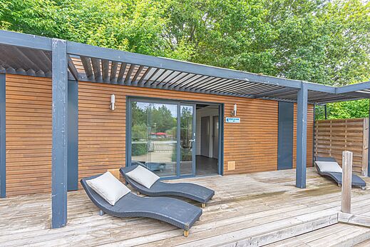 Modern mobile home with wooden deck and chairs at CAPFUN La Ch�naie campsite in PORNIC (44).