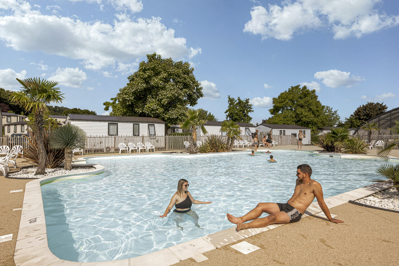 Outdoor swimming pool, couple and mobile homes at CLICOCHIC Chevaliers campsite, HOULGATE (14).