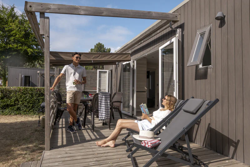 Modern mobile home with terrace, couple relaxing at CLICOCHIC Chouans campsite in SAINT HILAIRE DE RIEZ.