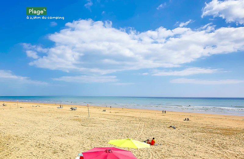 Fine sandy beach, sea and parasols at CLICOCHIC Chouans campsite in Saint Hilaire de Riez.