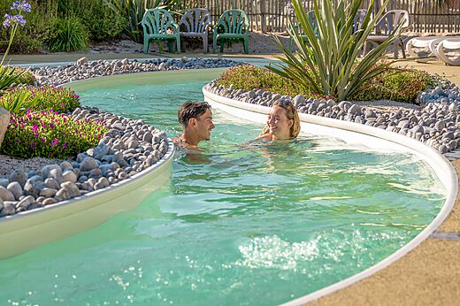 Lazy river pool with smiling couple at CLICOCHIC Chouans campsite in SAINT HILAIRE DE RIEZ (85).