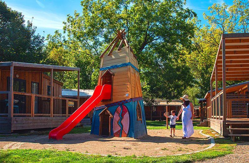 Playground with slide and accommodations at CLICOCHIC Au Clair Ruisseau campsite Gerstheim (67).