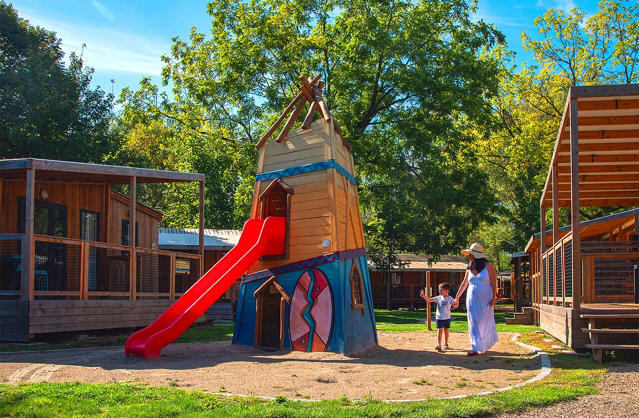 Playground with slide and accommodations at CLICOCHIC Au Clair Ruisseau campsite Gerstheim (67).