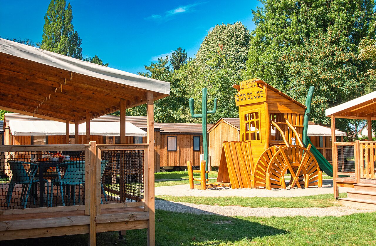 Western themed playground and accommodation terrace at CLICOCHIC campsite in Gerstheim (67).