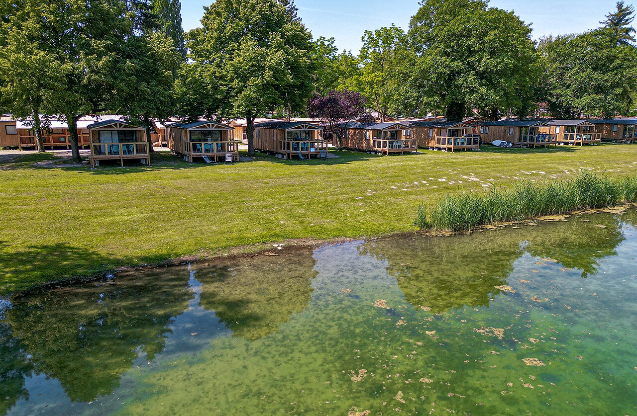 Wooden chalets by the water, campsite CLICOCHIC Au Clair Ruisseau in Gerstheim (67).