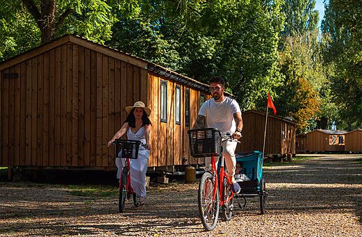Couple cycling with child past mobile homes, CLICOCHIC Gerstheim (67).