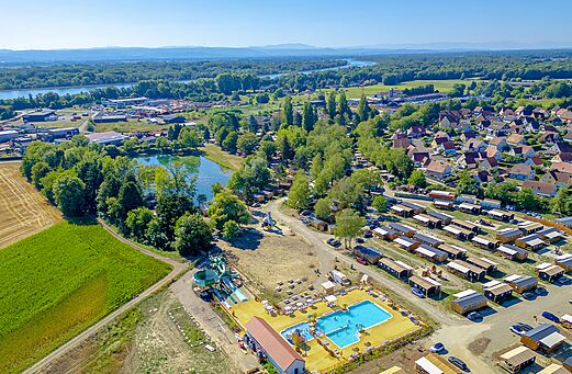 Aerial view swimming pool, water slides and Mobile homes at CLICOCHIC Au Clair Ruisseau campsite.
