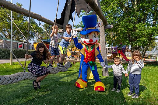 Mascot and children playing on the playground structure at CAPFUN Clown Océan campsite in TOSSE (40).