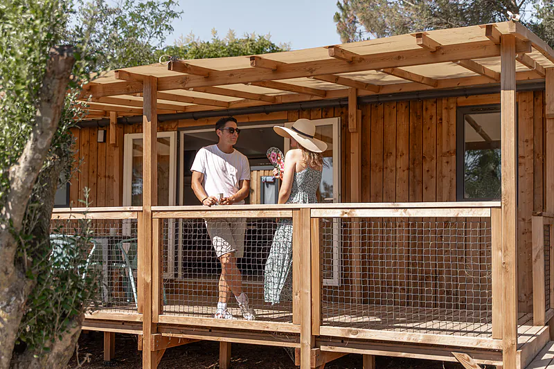 Couple on terrace of wooden mobile home at CLICOCHIC Commanderie Rustiques (11).