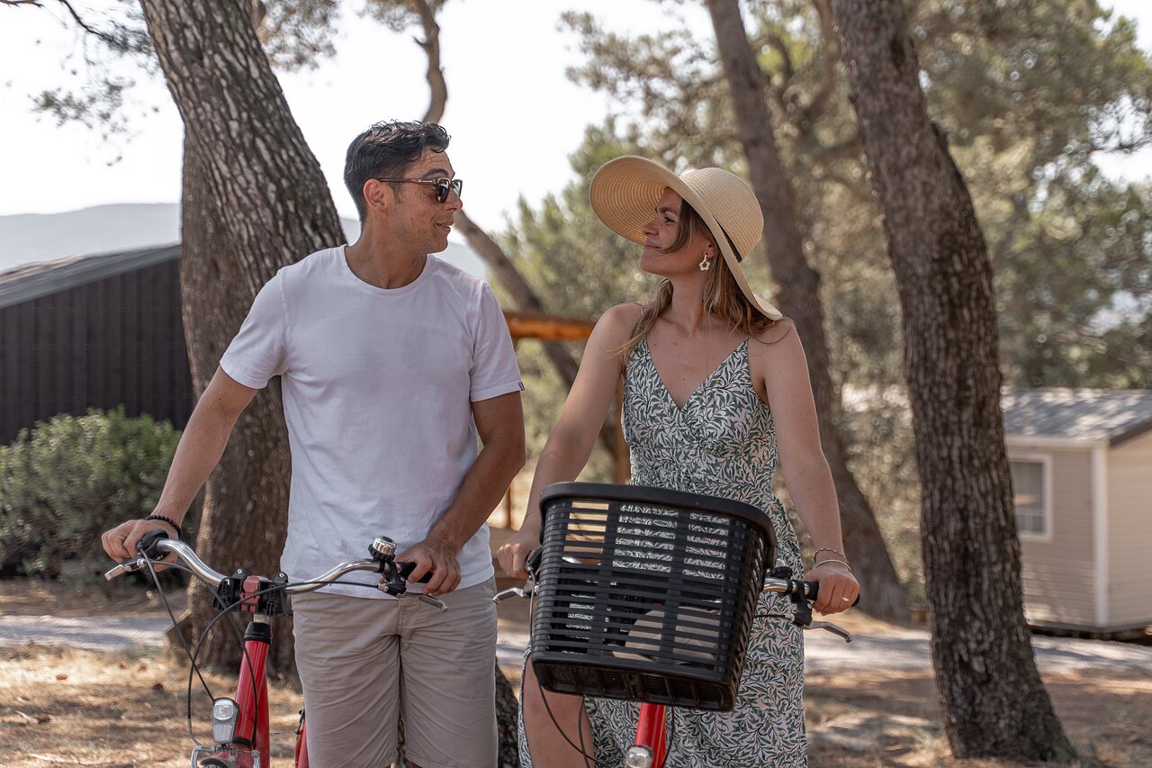 Smiling couple with bicycles in nature at CLICOCHIC Commanderie campsite Rustiques (11).