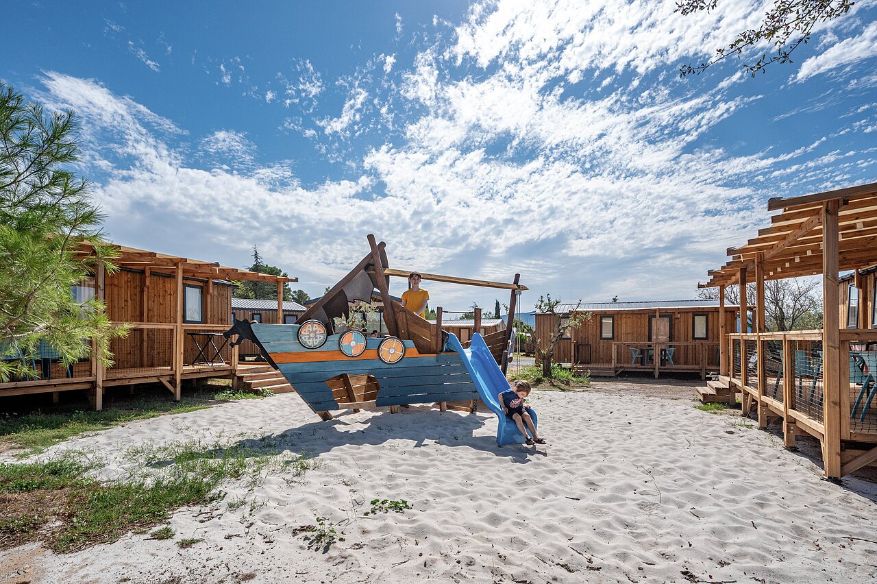 Viking ship playground, slide, children, mobile homes at CLICOCHIC Commanderie campsite.