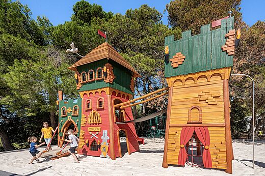 Wooden castle playground with children at CLICOCHIC Commanderie campsite in Rustiques.