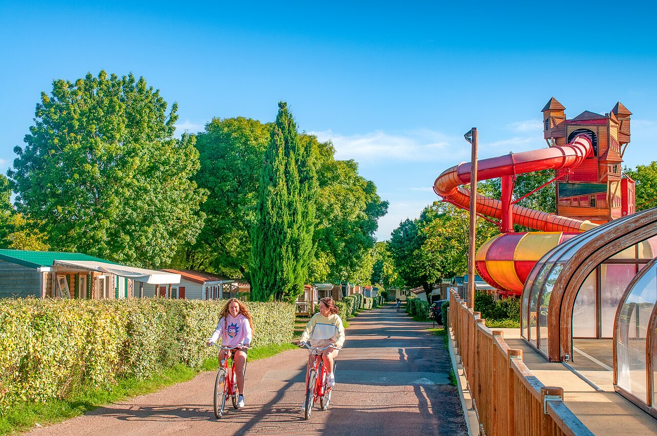 Young girls cycling, water slide, mobile homes at CAPFUN Coquelicots campsite in Royan (17).